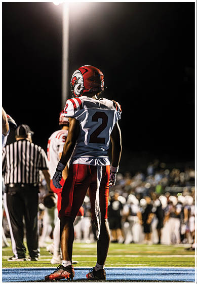 A football player wearing a blue and red jersey. Description generated by AI