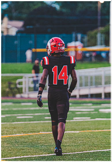 A football player wearing a blue and red jersey. Description generated by AI