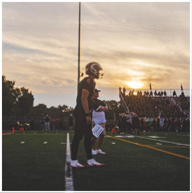 A football game is taking place with a group of men on the field. Description generated by AI