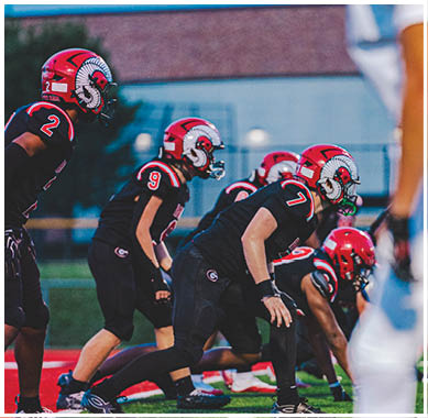 A football game is taking place with a group of men on the field. Description generated by AI