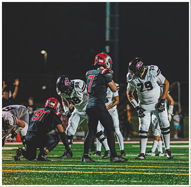 A football game is taking place with a group of men on the field. Description generated by AI
