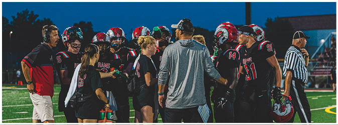 A football game is taking place on a field with players wearing blue and white uniforms. Description generated by AI