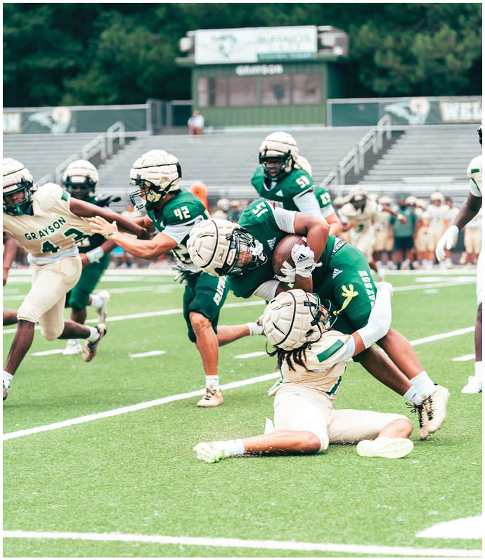 Three football players in blue and white uniforms running on a field. Description generated by AI