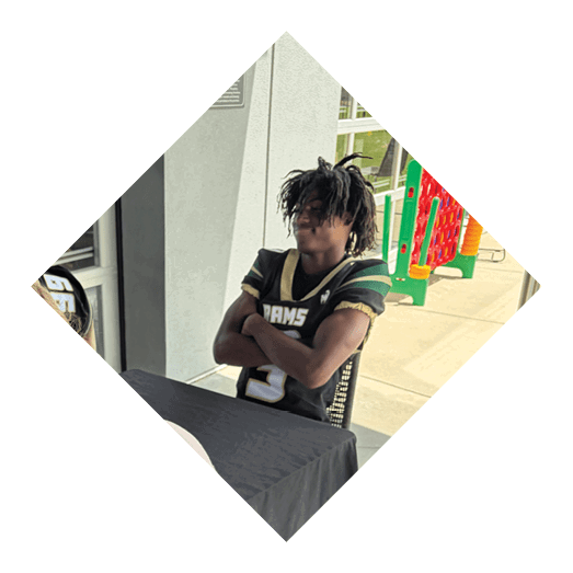 A football player wearing a black jersey with the number 10 sits on the ground with a football helmet on the ground next to him. AI generated content