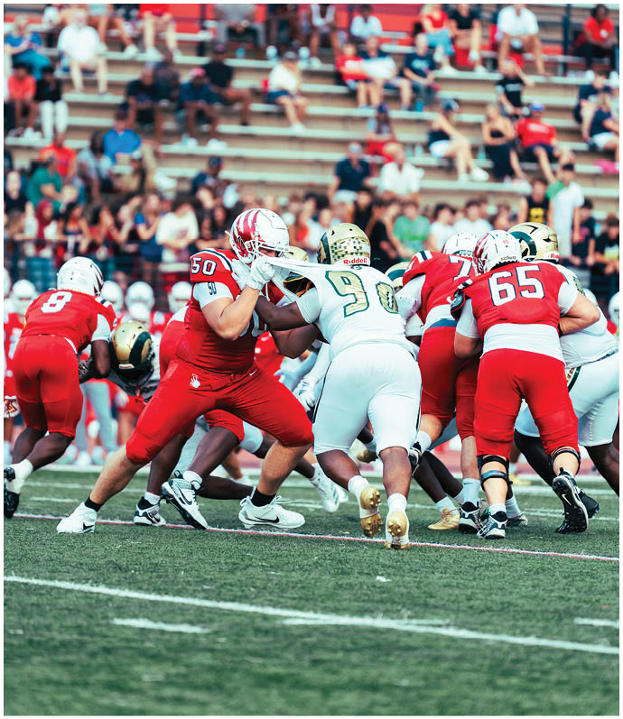 Three football players in blue and white uniforms running on a field. Description generated by AI