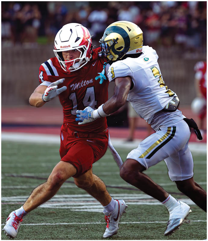 Three football players in blue and white uniforms running on a field. Description generated by AI
