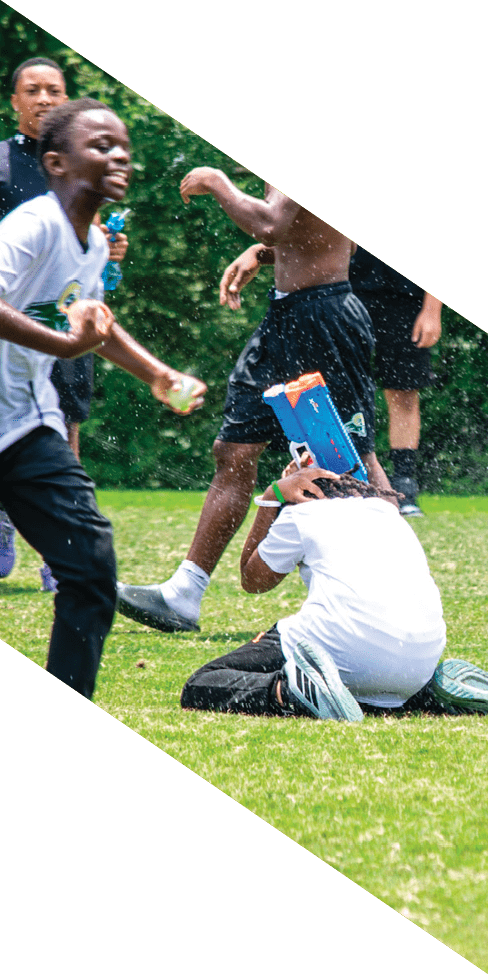 Two men are jumping in the air on a field, both wearing football uniforms. AI generated content