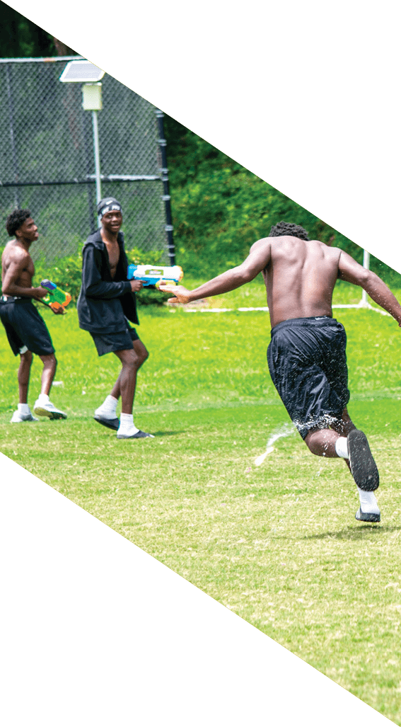 A football player wearing a black helmet and white jersey is holding a football in his hands. AI generated content