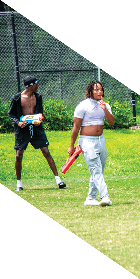 Two men are jumping in the air on a field, both wearing football uniforms. AI generated content
