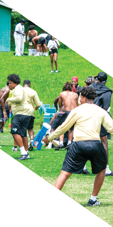 Two football players are on the field, one jumping in the air while the other is running. A referee is also present, watching the play. AI generated content