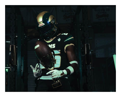 A man in a black jersey is running on a field with a football in his hand. AI generated content