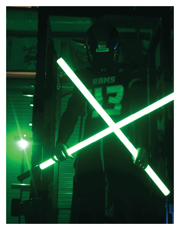 A football player wearing a helmet and white uniform is holding his helmet above his head. AI generated content