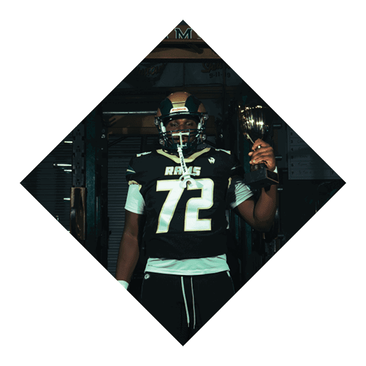A football player wearing a black jersey with the number 10 sits on the ground with a football helmet on the ground next to him. AI generated content
