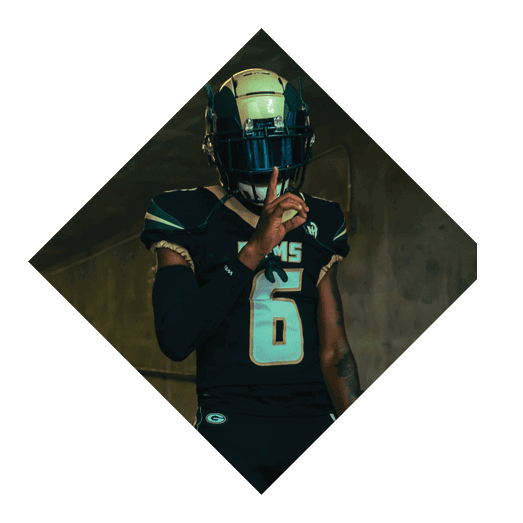 A football player wearing a black jersey with the number 10 sits on the ground with a football helmet on the ground next to him. AI generated content