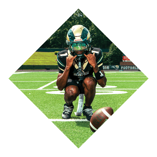 A football player wearing a black jersey with the number 10 sits on the ground with a football helmet on the ground next to him. AI generated content