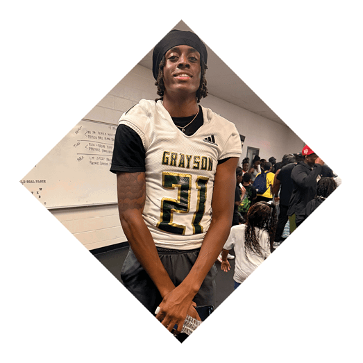 A football player wearing a black jersey with the number 10 sits on the ground with a football helmet on the ground next to him. AI generated content