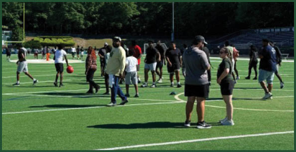 Three football players in blue and white uniforms running on a field. Description generated by AI
