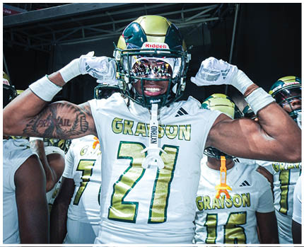 A person wearing a football helmet and gloves is flexing their arms and smiling inside a stadium with a “DISCOVER CAREERS" sign visible in the background. Description generated by AI