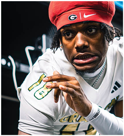 A person wearing a white sports jersey with the number 16 is making a focused or intense facial expression while adjusting their hand. Description generated by AI