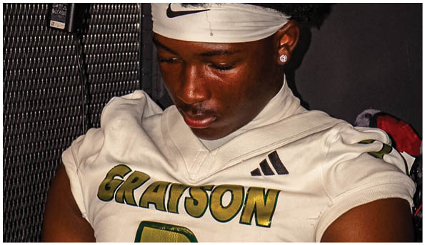 A person wearing a white football jersey with the word “GRAYSON" and the number 3 on it is sitting down. Description generated by AI