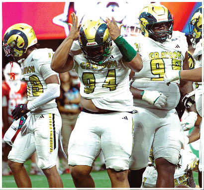 Two people wearing white football uniforms with numbers and gloves are standing close together on a field. Description generated by AI