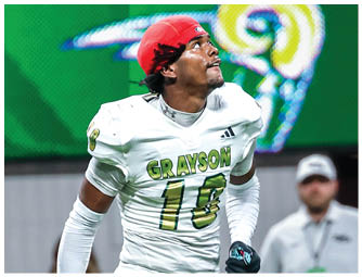 A person in a white football uniform with the word Grayson and the number 16 is running on a field holding a gold helmet and looking upward while people stand in the background. Description generated by AI