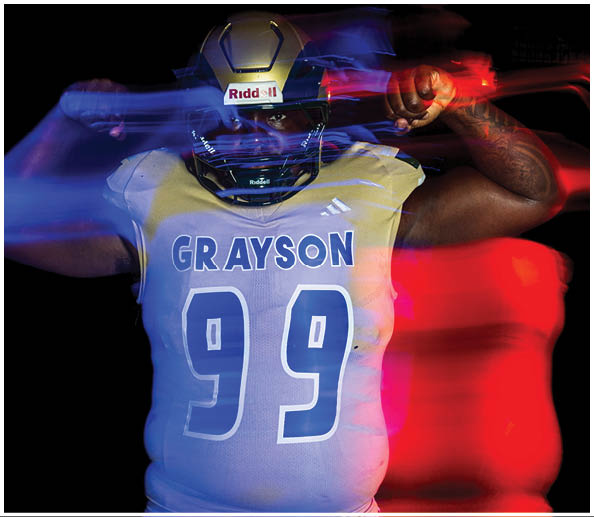 A person wearing a football helmet and jersey with the name Grayson and number 99 is captured in motion with red and blue light trails against a dark background. Description generated by AI