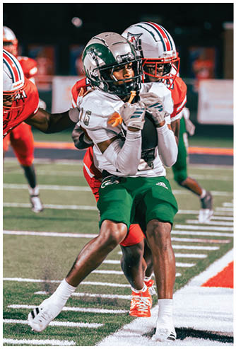 Two people in football uniforms are engaged in a tackle on a field during a game at night. Description generated by AI