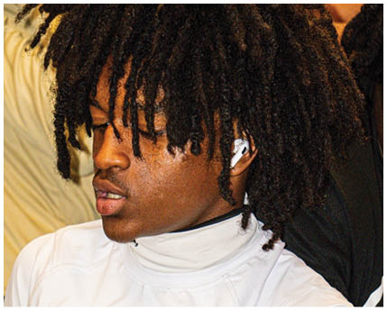 Person with thick, textured dreadlocks wearing a white wireless earbud. Description generated by AI