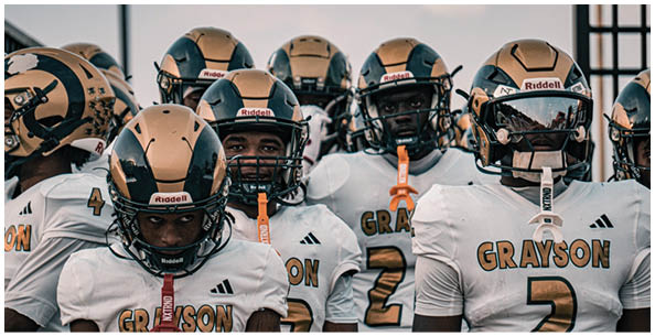 A group of people wearing white football uniforms and gold helmets stand closely together, appearing focused and ready for a game. Description generated by AI