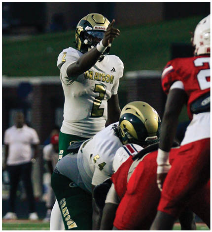 A person wearing a white and green football uniform with the number 2 and the name Grayson is giving a thumbs-up gesture on a football field. Description generated by AI