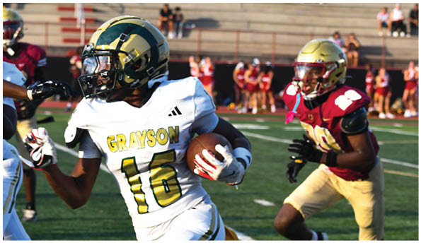 A person wearing a white football uniform with “Grayson" on the jersey is running with a football while another person in a maroon and gold uniform is chasing them on a football field. Description generated by AI