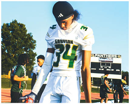 A person wearing a football helmet and a white jersey with the word Grayson and the number 10 stands outdoors with trees in the background. Description generated by AI