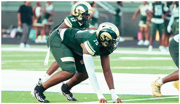 A person wearing a white football uniform with “Grayson" on the jersey is running with a football while another person in a maroon and gold uniform is chasing them on a football field. Description generated by AI