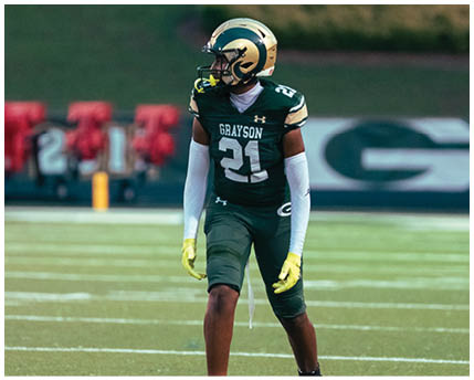 A person wearing a white football uniform and a green and gold helmet is running on a field while holding a football. Description generated by AI