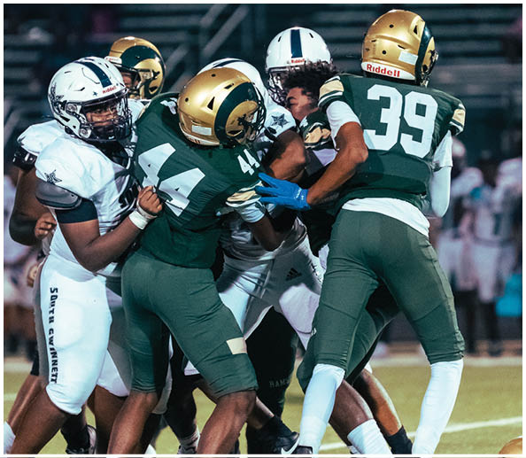 Two people in football uniforms are on a field with one person holding a football and preparing to run while the other person is in pursuit. Description generated by AI