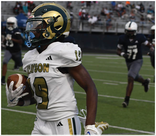 A person wearing a green football jersey with the number 86 and a yellow helmet stands on a football field. Description generated by AI