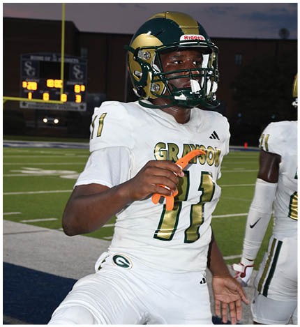 A person wearing a green sports jersey with the number 71 and white gloves is standing on a field. Description generated by AI