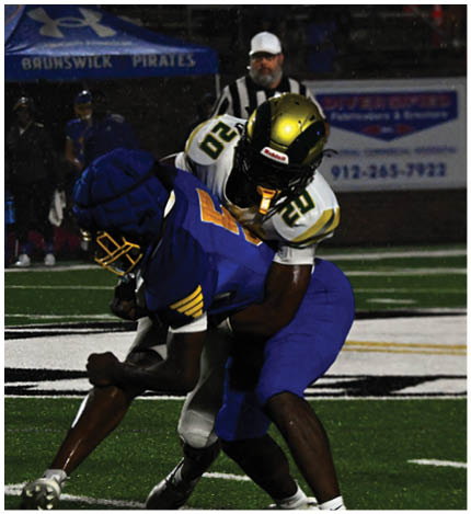 A person with long dreadlocks wearing a white football jersey with the name Grayson and the number 28 stands in front of two other people in similar football uniforms and helmets. Description generated by AI
