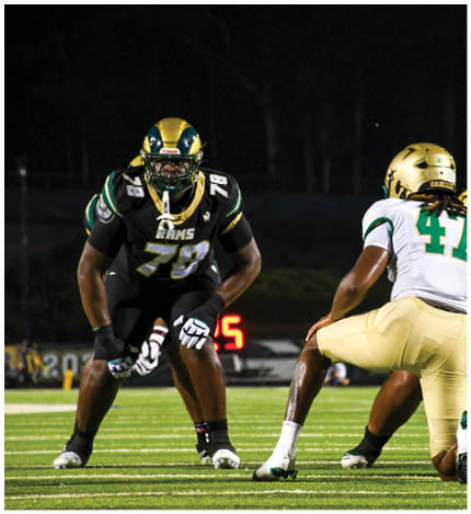A person with long dreadlocks wearing a white football jersey with the name Grayson and the number 28 stands in front of two other people in similar football uniforms and helmets. Description generated by AI