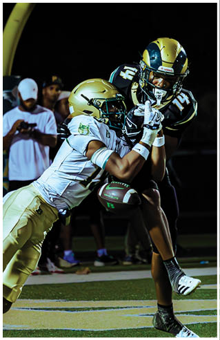 A person wearing white athletic pants and cleats is standing on a green football field with white yard lines. Description generated by AI