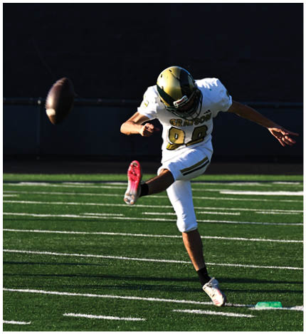 A person with long dreadlocks wearing a white football jersey with the name Grayson and the number 28 stands in front of two other people in similar football uniforms and helmets. Description generated by AI