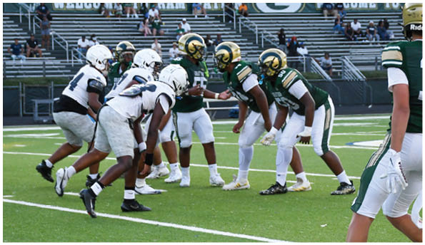 A person wearing white athletic pants and cleats is standing on a green football field with white yard lines. Description generated by AI