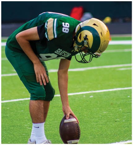 A person wearing a white football uniform with the number 13 is walking on a field toward a group of similarly dressed players standing on the sidelines. Description generated by AI