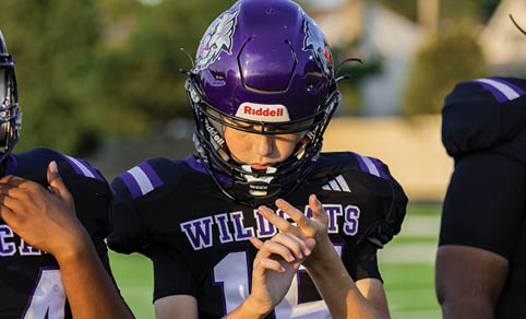 Two men wearing football uniforms are hugging each other on a field. AI generated content