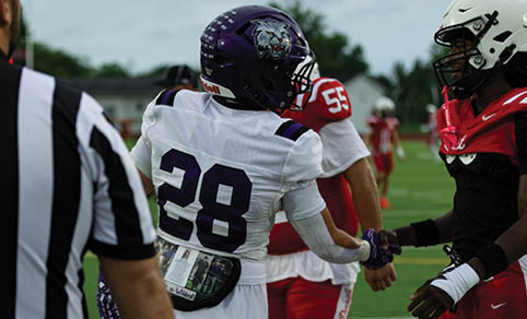 Two men wearing football uniforms are hugging each other on a field. AI generated content