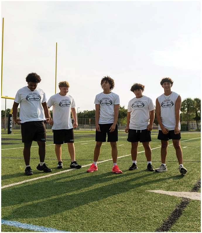 A group of young men standing on a football field. Description generated by AI