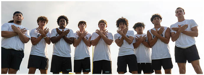 A group of people posing for a picture on a field. Description generated by AI