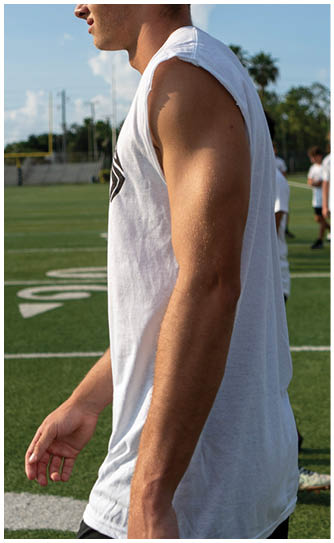 A man wearing a white shirt and black shorts walks on a field. Description generated by AI