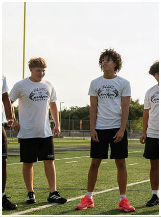 A group of young men standing on a football field. Description generated by AI